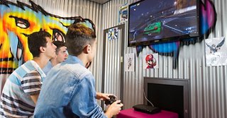 Zwei junge Erwachsene genießen gemeinsam eine Spielsession in einem lebhaften Unterhaltungsbereich | MSC Cruises