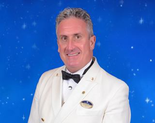 Crew officer posing with name badge and confident expression | MSC Cruises