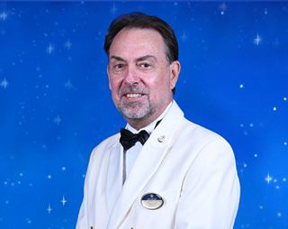 Captain in a white uniform with a smile, set against a blue background | MSC Cruises