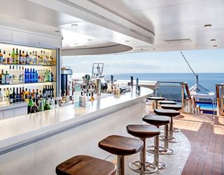 A vibrant outdoor bar area on the cruise ship with seating and a stunning sea view | MSC Cruises