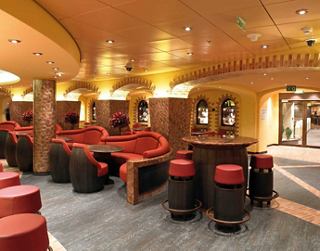 Espacio acogedor con sillas rojas y un bar para reuniones informales | MSC Cruceros