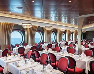Bright and elegant restaurant setting with red chairs and windows offering a beautiful view | MSC Cruises