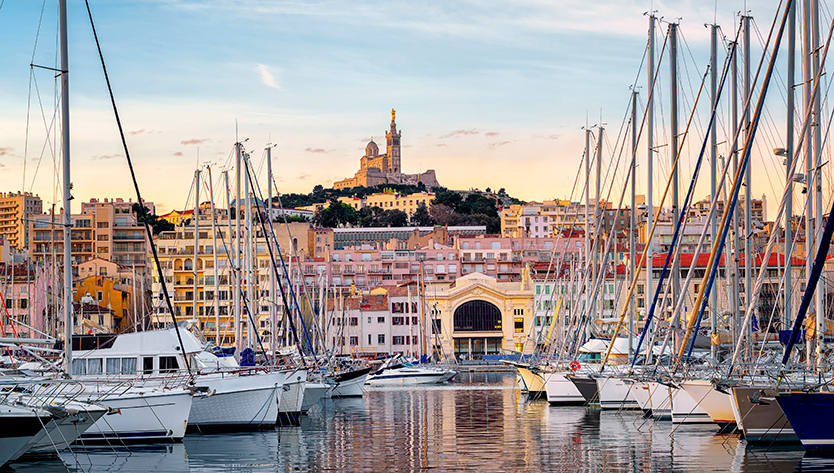 Une vue pittoresque de la marina au coucher du soleil, avec des bateaux et la skyline de Marseille en arrière-plan | MSC Cruises