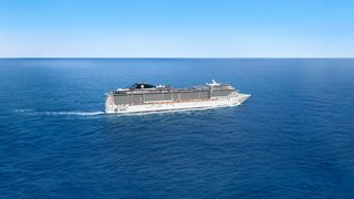 Ein majestätisches Kreuzfahrtschiff segelt über das ruhige blaue Meer unter einem klaren Himmel | MSC Cruises