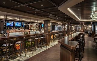 Eine gemütliche Bar mit einem langen Holztisch und bequemen Sitzgelegenheiten, ideal für gesellige Zusammenkünfte | MSC Cruises