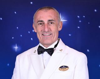 Crew member in uniform shown in well-lit indoor space | MSC Cruises