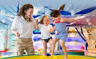 A joyful adult and two children play together on a colourful bouncy surface, fostering fun and laughter | MSC Cruises