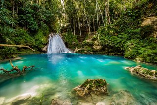 Waterfall surrounded by lush forest and turquoise river in Jamaica’s Blue Hole | MSC Cruises