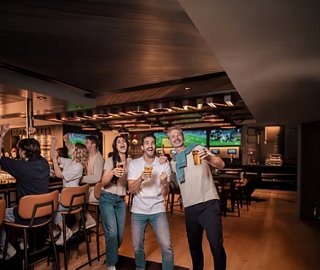 Guests enjoy drinks in a lively sports bar with contemporary décor | MSC Cruises