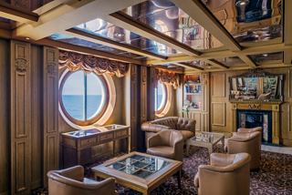Ambassador Room on MSC Sinfonia features cozy seating and round windows overlooking the sea | MSC Cruises