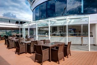 Outdoor seating area with tables and chairs near Atmosphere Ice Cream Bar on MSC Meraviglia deck | MSC Cruises