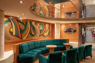 Spacious lounge with green sofas and tables surrounded by vibrant wall art | MSC Cruises