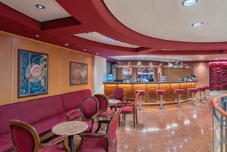 Spacious lounge featuring a bar counter, tables and comfortable seating for onboard relaxation | MSC Cruises
