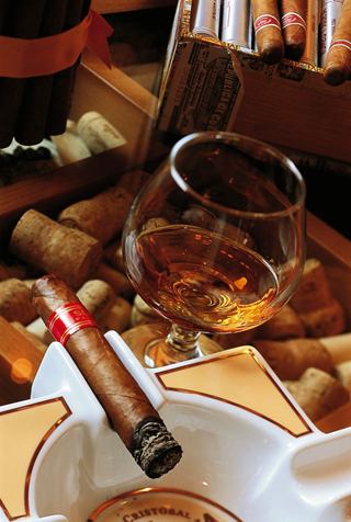 A glass of beverage and cigar in ashtray on wooden table in an inviting setting | MSC Cruises