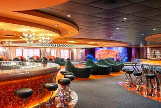 Spacious lounge with tables, armchairs, bar counter and stage for music on MSC Fantasia | MSC Cruises