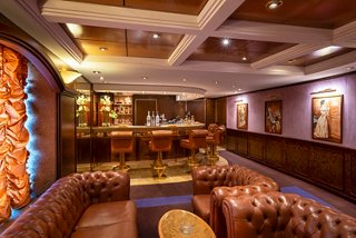 Inviting sitting area with bar and leather sofas in La Cubana lounge aboard MSC Orchestra | MSC Cruises