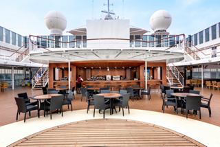 Outdoor bar with tables and chairs on the deck beneath an open sky | MSC Cruises