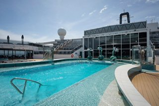 Pool with sunbeds, sitting area, sculpture and stairs on MSC World America | MSC Cruises