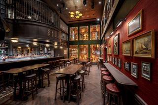 Double-deck Masters of the Sea pub with bar counter, tables and footstools, inviting ambiance | MSC Cruises