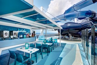 Polar Bar on MSC Meraviglia with tables, poolside seating and a waterslide overlooking the sea | MSC Cruises