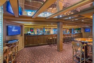 Spacious Irish pub featuring wooden accents and screens for relaxing and gathering | MSC Cruises
