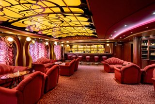Welcoming seating area with red sofas and warm lighting in The Cigar Lounge | MSC Cruises