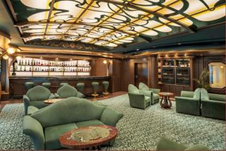 Elegant lounge with plush green seating and a refined bar area for relaxation | MSC Cruises