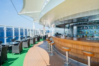The Garden Bar features wooden seating and tables on the outdoor deck overlooking the sea | MSC Cruises