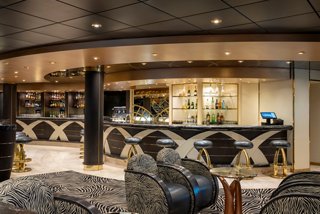 Seating area with stylish armchairs and bar counter aboard MSC Poesia | MSC Cruises