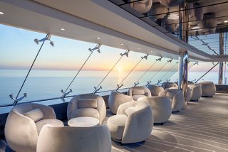 Top Sail Lounge features cozy armchairs and panoramic sea views at sunrise | MSC Cruises