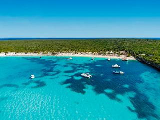 Karibische Insel mit Strand, türkisfarbenem Meer, Booten und Palmen nahe Dominikanische Republik | MSC Cruises