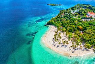 Caribbean island with turquoise sea, white sand beach and resort surrounded by greenery | MSC Cruises