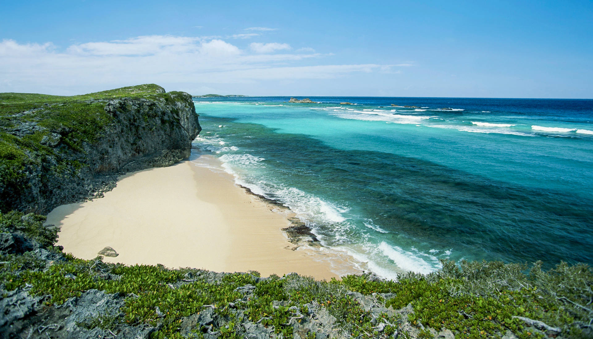 Sandy beach on Grand Turk with turquoise sea and lush vegetation | MSC Cruises