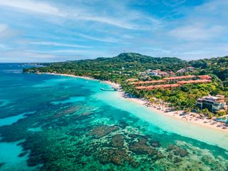 The coastline of Isla de Roatan in Honduras with turquoise sea, beach and lush hills | MSC Cruises