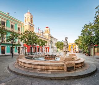 Fountain at Plaza de Armas in San Juan surrounded by colorful buildings and green trees | MSC Cruises