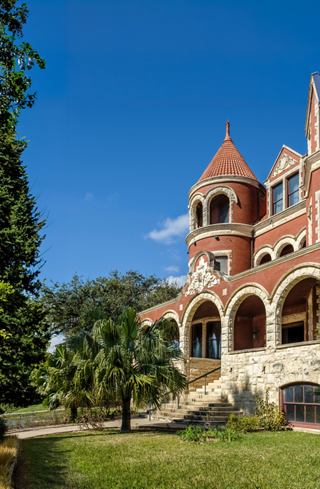 A historic mansion with arched windows and lush greenery beneath a clear blue sky | MSC Cruises