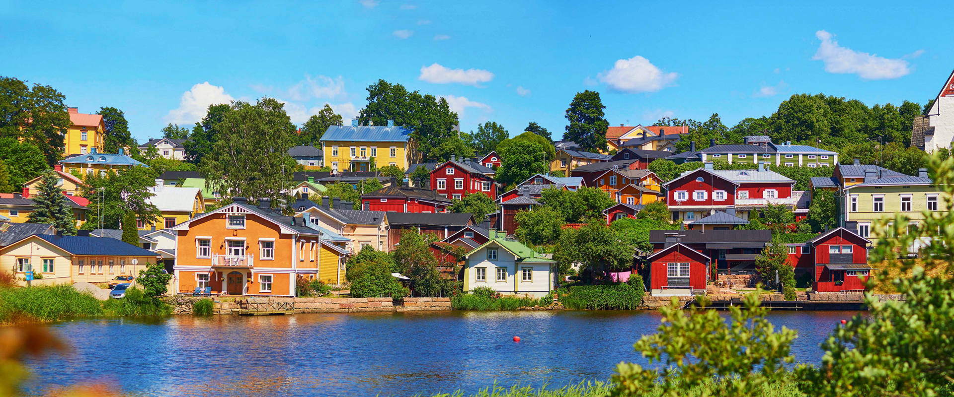 Colorful houses by the river in Porvoo, Finland surrounded by lush greenery | MSC Cruises