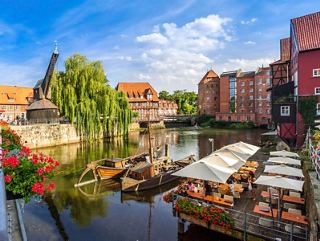 Lüneburg’s old port with boats, waterfront cafés, historic buildings and vibrant flowers | MSC Cruises