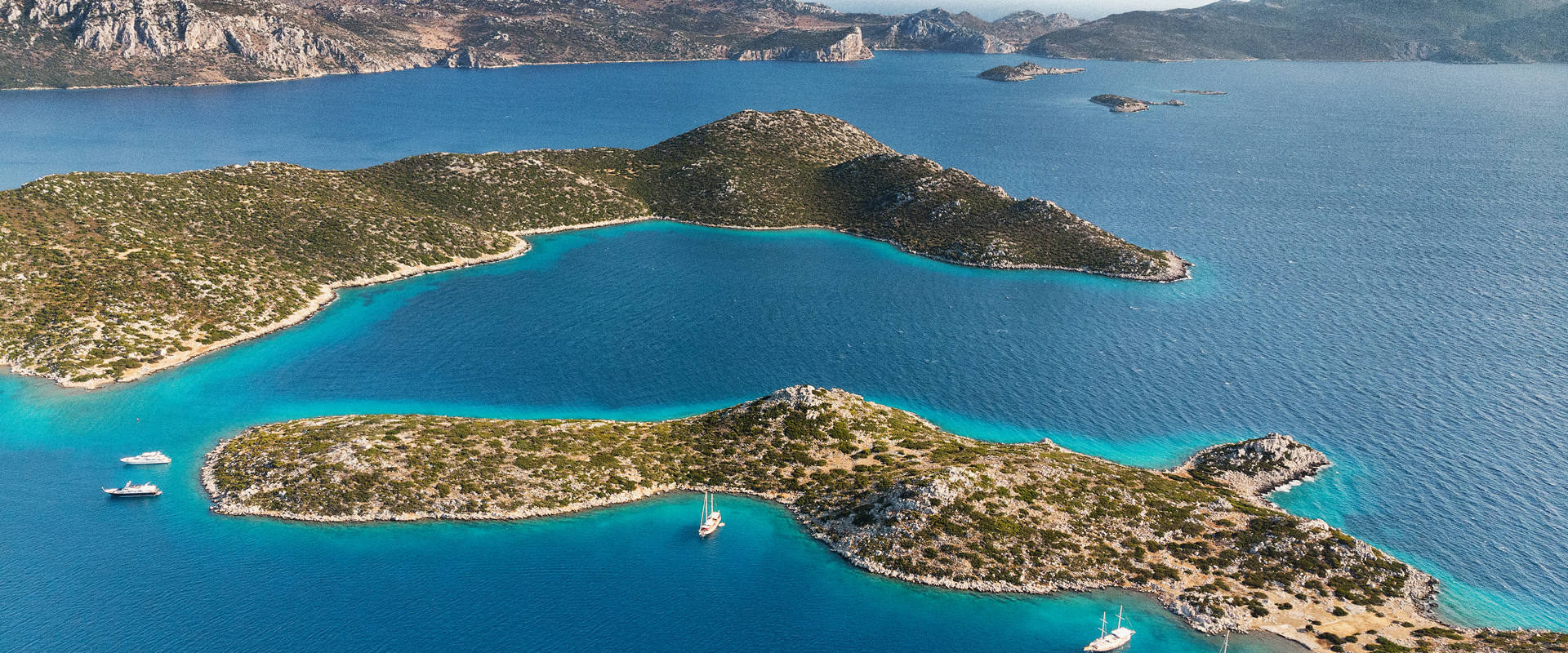 Turquoise sea surrounds lush islands and distant mountains along the coastline | MSC Cruises