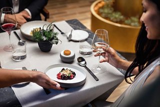 A couple enjoys a gourmet dinner as a waiter serves their dish | MSC Cruises