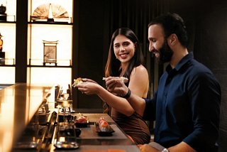 Two people enjoy sushi together in a warm and inviting restaurant setting | MSC Cruises