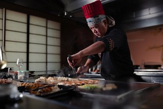 Chef prepares teppanyaki dishes on the grill in a welcoming restaurant setting | MSC Cruises