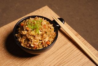 A bowl of rice with vegetables and chopsticks arranged on a wooden surface | MSC Cruises