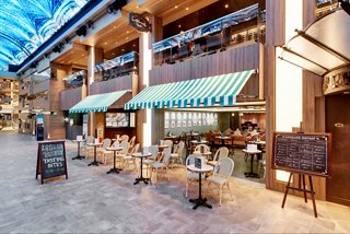 Entrance to L'Atelier Bistrot on MSC Grandiosa with tables set along the promenade | MSC Cruises