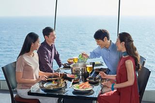 Four people share a meal with a sea view at Sea Pavilion restaurant on board | MSC Cruises