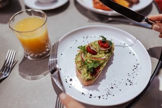 A glass of juice and toast topped with avocado and vegetables on a dining table | MSC Cruises