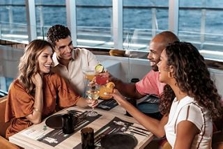 A group of people share a toast at a table on a cruise ship with an ocean view | MSC Cruises