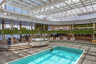 Spacious indoor pool with bar and green accents aboard MSC Seascape | MSC Cruises
