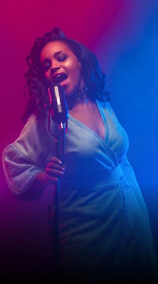 A woman performs on stage holding a microphone, surrounded by vibrant colored lights | MSC Cruises