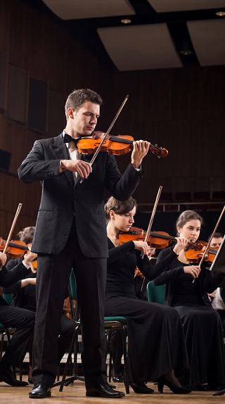 Musicians perform orchestral music on stage in an elegant setting | MSC Cruises